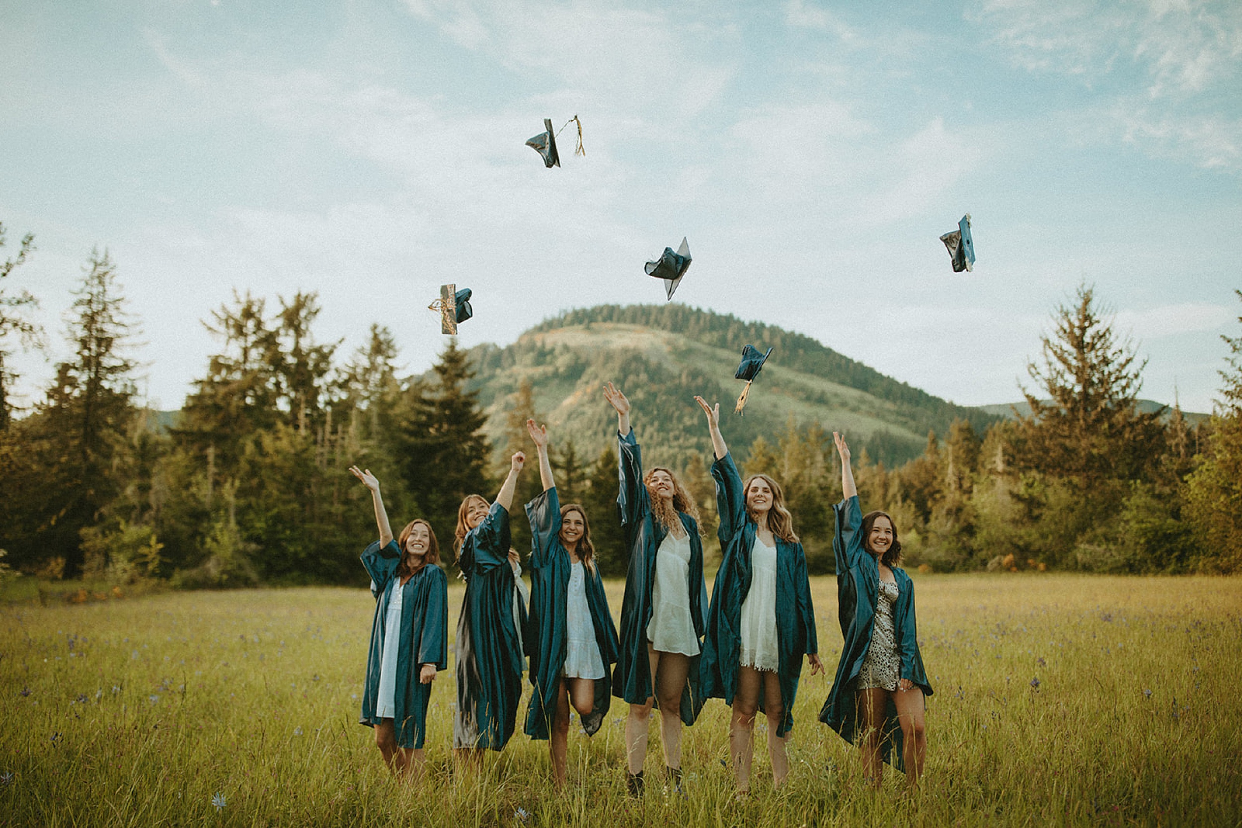 graduates standing in a field throwing caps