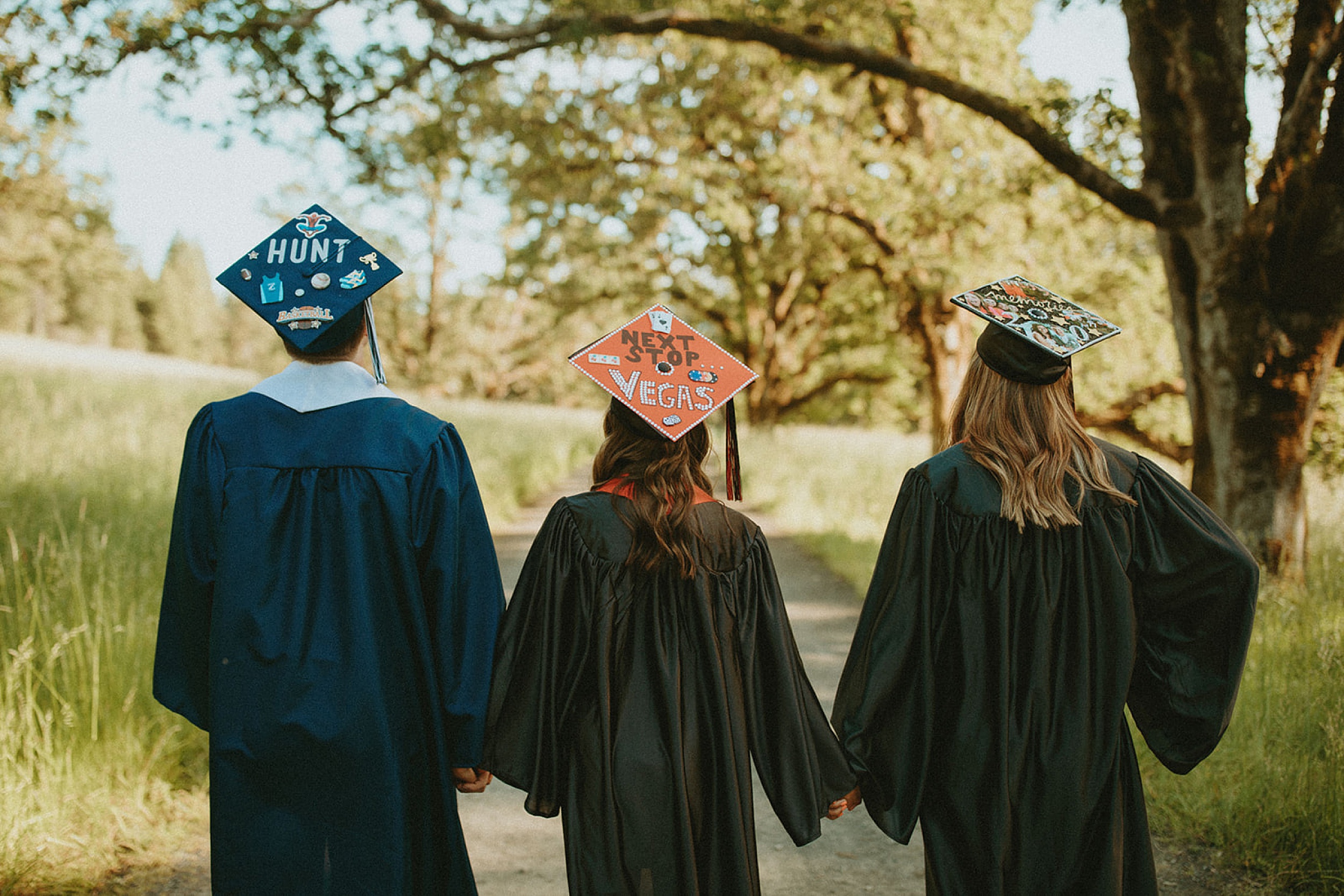 friends holding hands in their cap and gowns